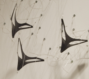 Close-up of a sculpture made made from spandex and objects resembling military planes flying down towards the ground.