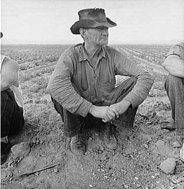 A man sitting on the ground of a field.