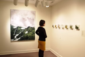 A woman in a gallery looking at a painting.