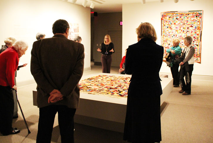 On Member Preview Day, visitors examine quilts on a tour led by Associate Curator Virginia Treanor