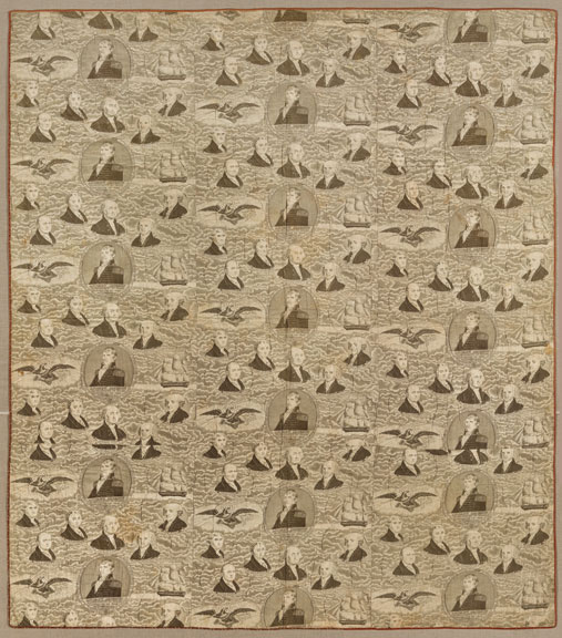 A beige quilt featuring the heads of presidents and the American eagle repeatedly.