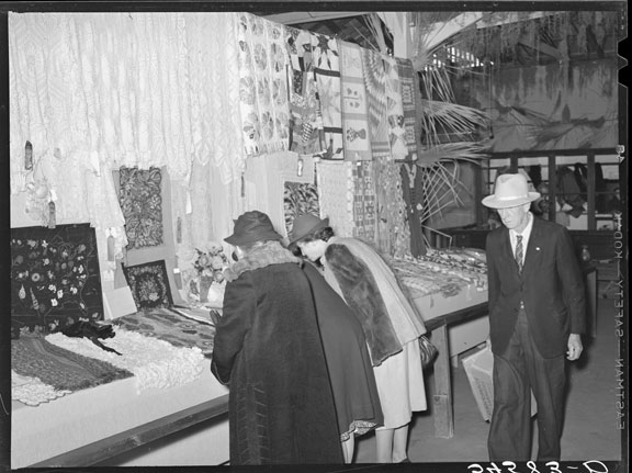 Women looking at quilting and crocheting exhibit at a county fair.