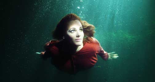Screenshot of a video showing a woman swimming under water.