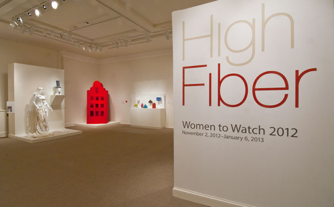 Installation view of a gallery space. There are several sculptures on one side, and the exhibition title "High Fiber—Women to Watch 2012" on the other wall.