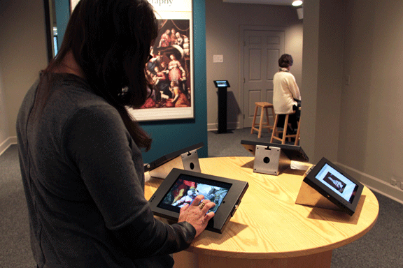 A museum visitor is using a digital display in a gallery.