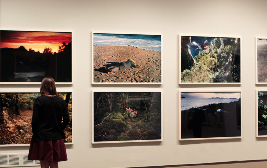 Installation view of a gallery space, Several large photographs hang on a white wall.