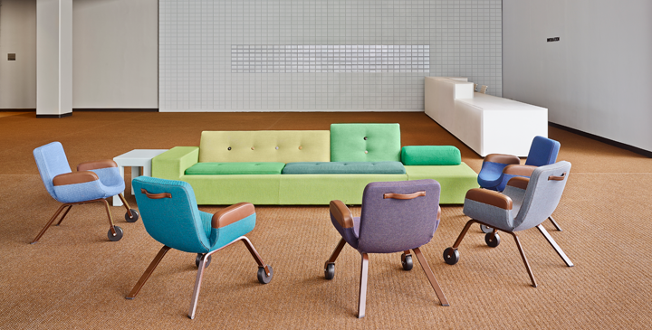 A colorful sofa and colorful chairs are standing in a circle.