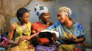 Three women with a dark skin tone are sitting next to each other.