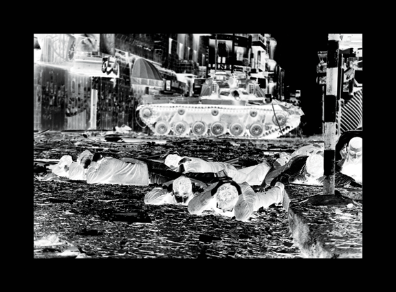 A photo negative in black and white depicting a war scene in the streets of a city. People are lying on the ground covering their heads as a tank drives by.
