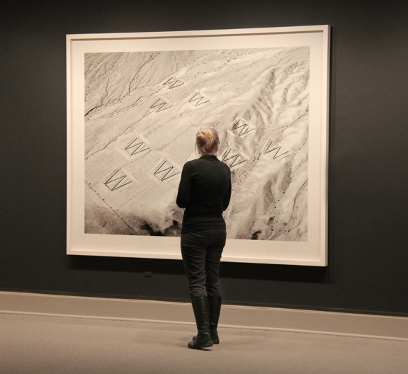 A museum visitor views a large work of art hanging on a wall.
