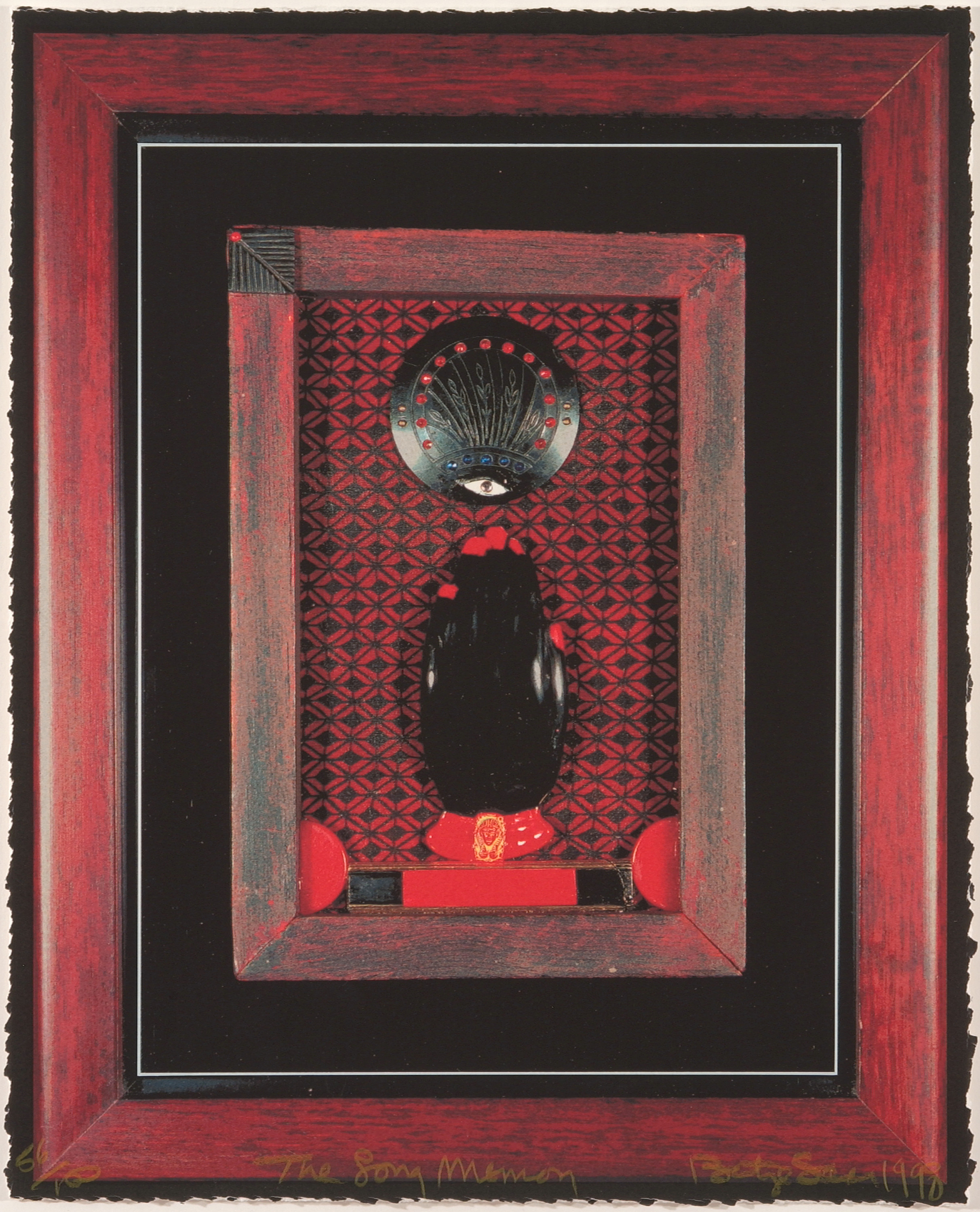 A black left hand with bright red nails and a red bracelet in a red wooden frame. It sits atop a black and red patterned background, fingers pointing toward a black medallion with an eye and other details. The red frame is surrounded by black and sits within a larger red frame.