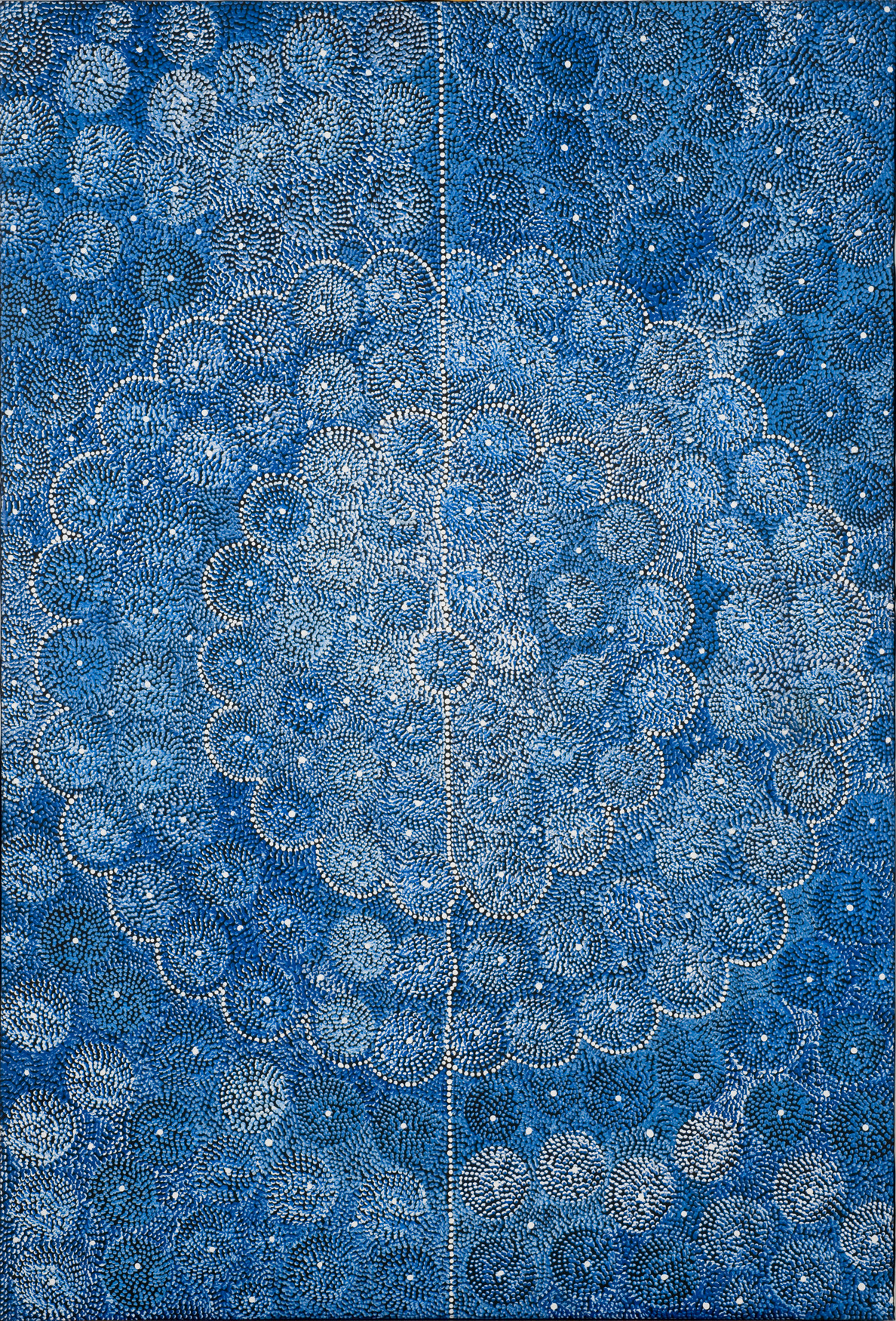 Tiny dots in white and various, rich shades of blue arranged to form circles. The circles are arranged into larger, concentric, white scallop-edged blue circles with a white dotted line going down the center.