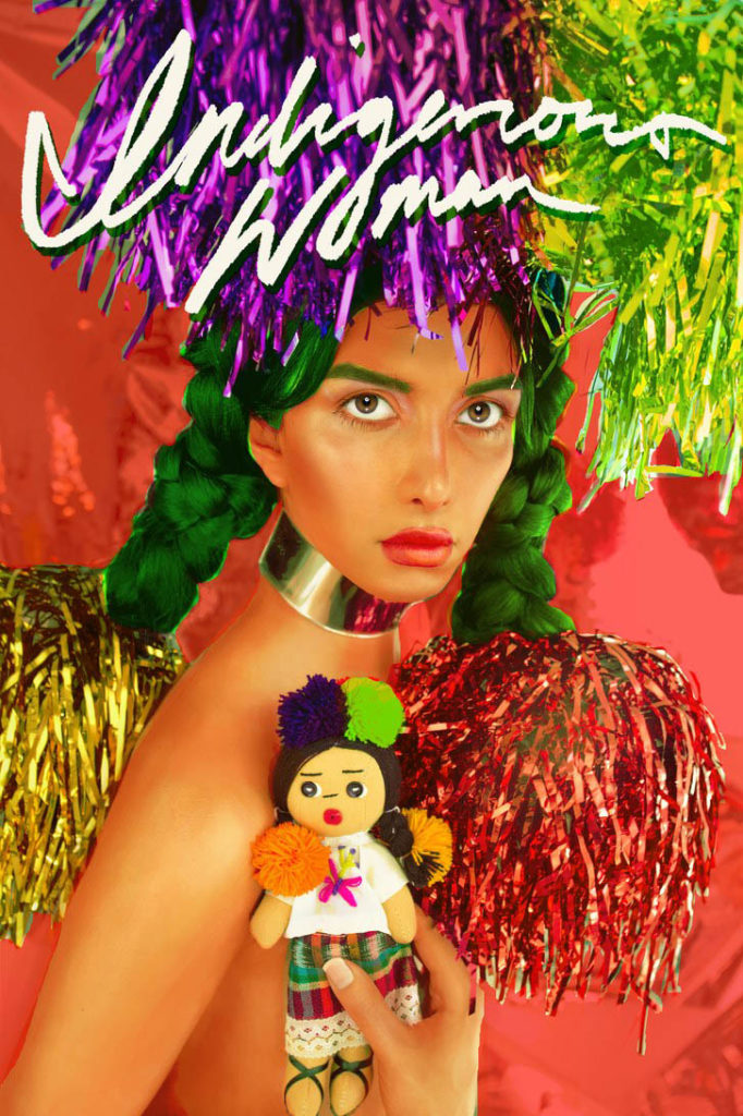 A photograph of a woman wearing green pigtails and colorful, metallic pom poms in her hair. She looks into the camera and is holding a small doll made out of fabric. In big, white letters it says "Indigenous Women" on top of the photograph.