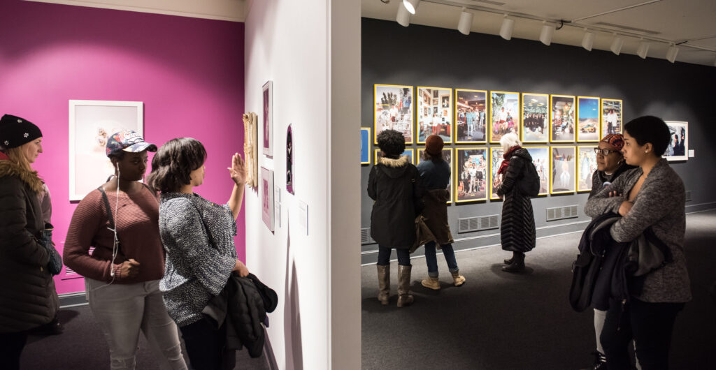 Eight diverse women museum visitors are scattered throughout the NMWA collection galleries browsing the art on the walls.