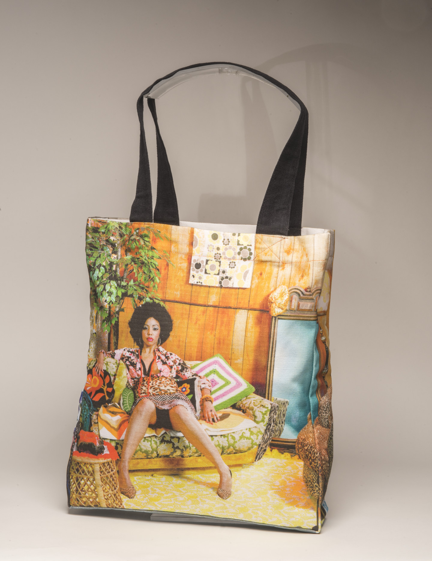 A tote bag with a photograph of a woman with a dark skin tone sitting on a sofa.