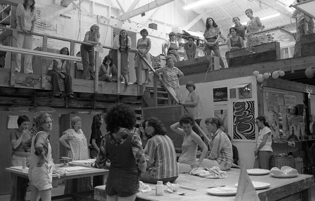 In this black and white photo, Judy Chicago addresses a gathering of volunteers in the Dinner Party studio, ca. 1978.