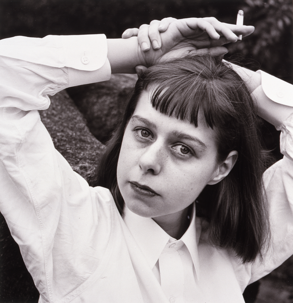 Louise Dahl-Wolfe's black and white portrait of Carson McCullers, who poses in a white oxford shirt with her hands above her head, the left clasping a cigarette.