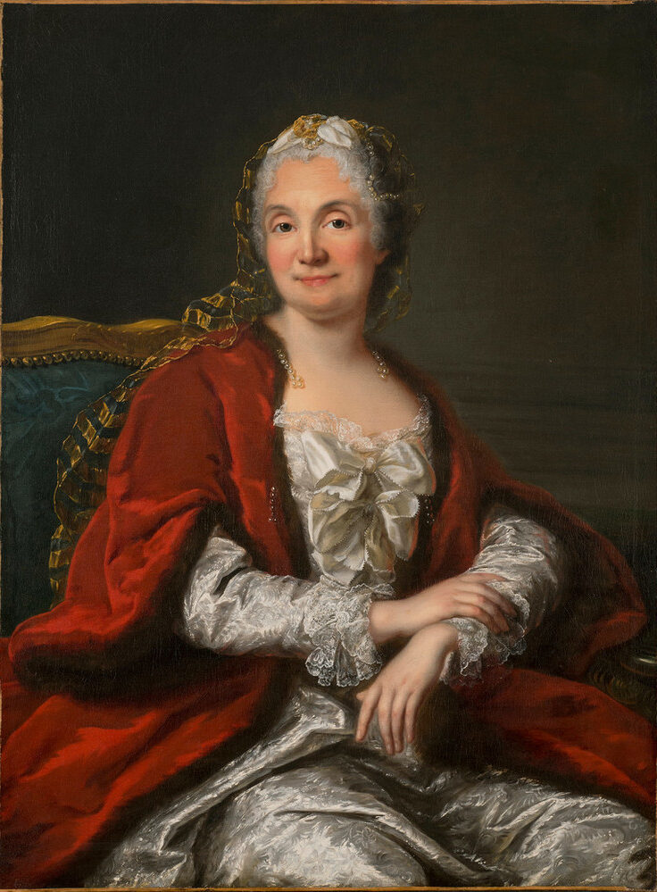 A light-skinned, gray-haired woman appears from the waist up, sitting with arms crossed loosely in her lap. Her body turns to her left, but she faces the viewer offering a slight smile and making eye contact. Her white satin gown and fur- and pearl-trimmed red cape imply wealth.