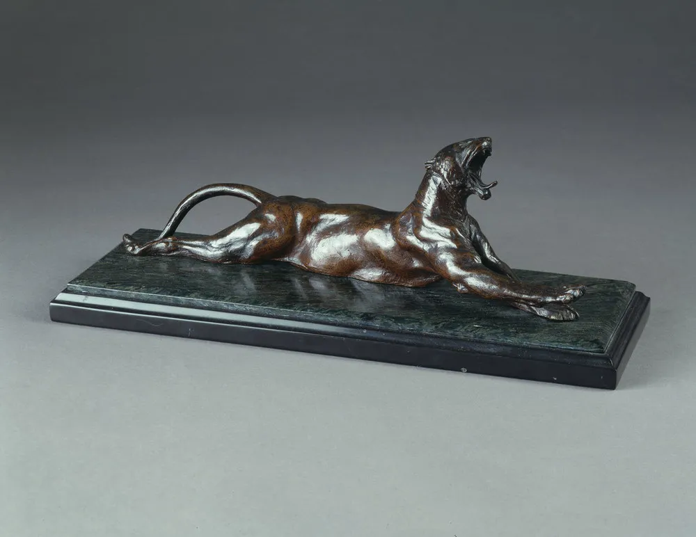 Bronze sculpture set on a polished green-gray stone base depicts a muscular panther with arched back and tail. The animal lies on its belly and stretches front and back legs out while opening its jaw in a convincing yawn, tongue protruding and teeth bared.