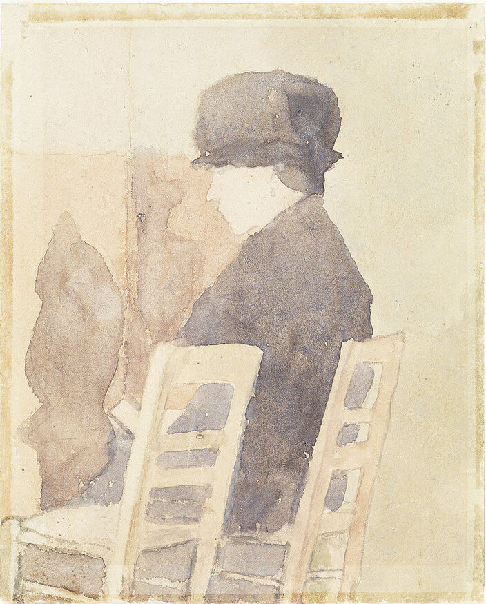 Watercolor sketch rendered in muted neutral tones, features a light-skinned woman sitting in a ladderback chair parallel to the viewer, with an identical empty chair next to her in the foreground. The woman wears a dark hat and coat, her head bent forward reading a paper in her lap.