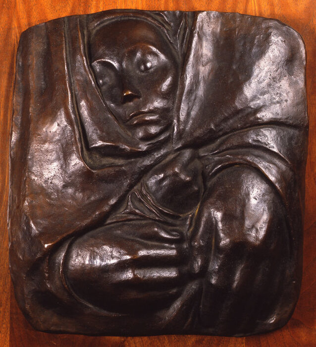A small face, hands and the suggestion of shoulders form a square bronze relief with rounded corners. The face, on top, looks slightly right, as a pair of hands gather the fabric towards the lower left corner. The fabric folds and creases, forming almost a swirl into the center.