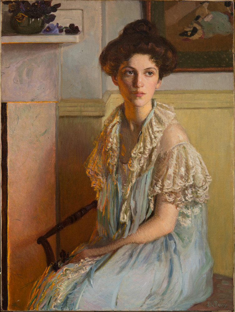 A young woman sits on a chair with her hair in a loose bun, wearing a white lace-trim gown. Her body turns slightly right towards a fireplace, its orange glow reflected on her hair and torso. The room is light and clean and a dark bowl overflowing with violets sits on the mantle.