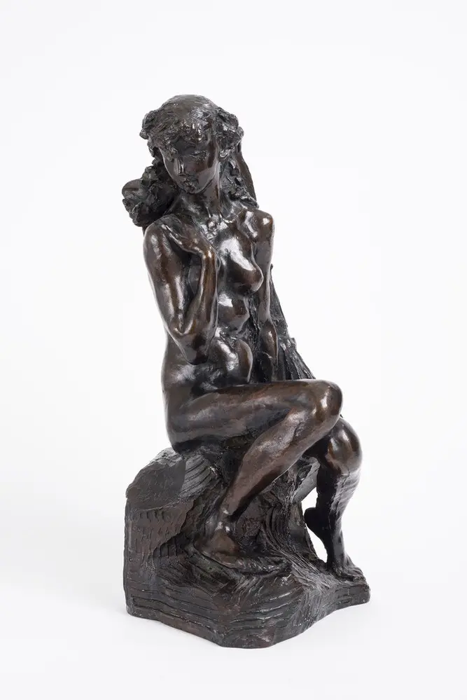 Bronze tabletop sculpture depicting a nude young woman seated on rough-hewn base.leaning against a sheaf of wheat, The figure's knees are drawn together, her left arm hanging at her side and her right arm bent upwards, clasping her shoulder.