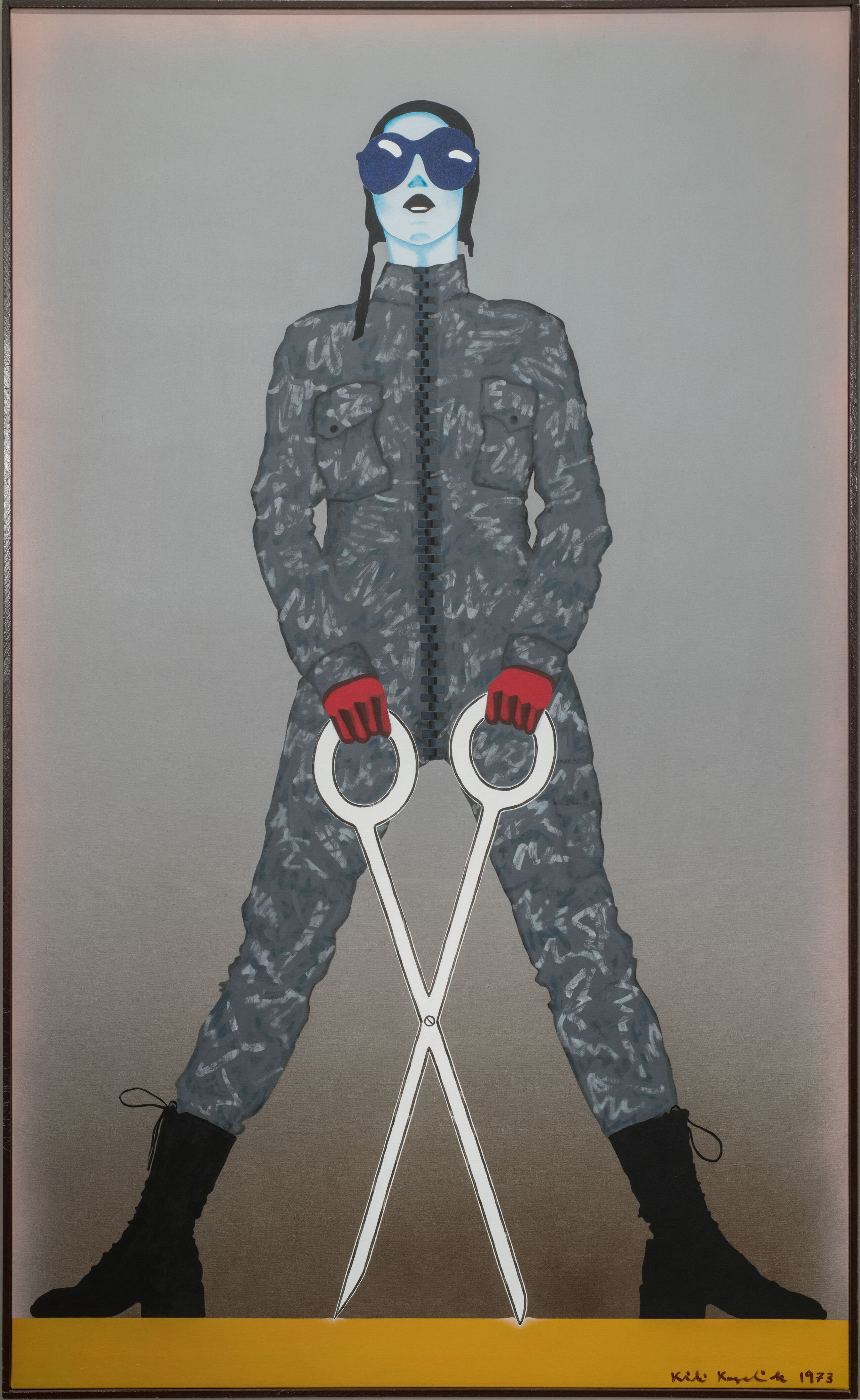 A monumental figure sports a gray camouflage jumpsuit, black army boots, red gloves, and an aviator cap with goggles. Legs splayed, the standing figure wields oversized, white scissors open in an X-shape. The linear style, bulbous eyewear, and cartoonish weapon evoke comic books.
