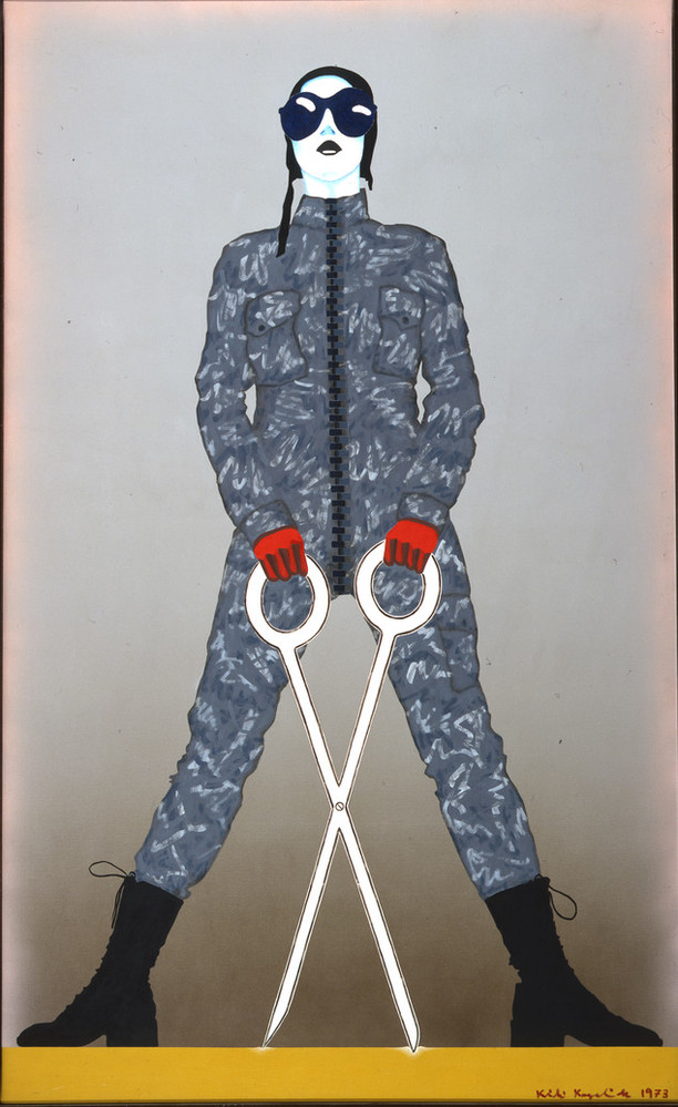 A monumental figure sports a gray camouflage jumpsuit, black army boots, red gloves, and an aviator cap with goggles. Legs splayed, the standing figure wields oversized, white scissors open in an X-shape. The linear style, bulbous eyewear, and cartoonish weapon evoke comic books.