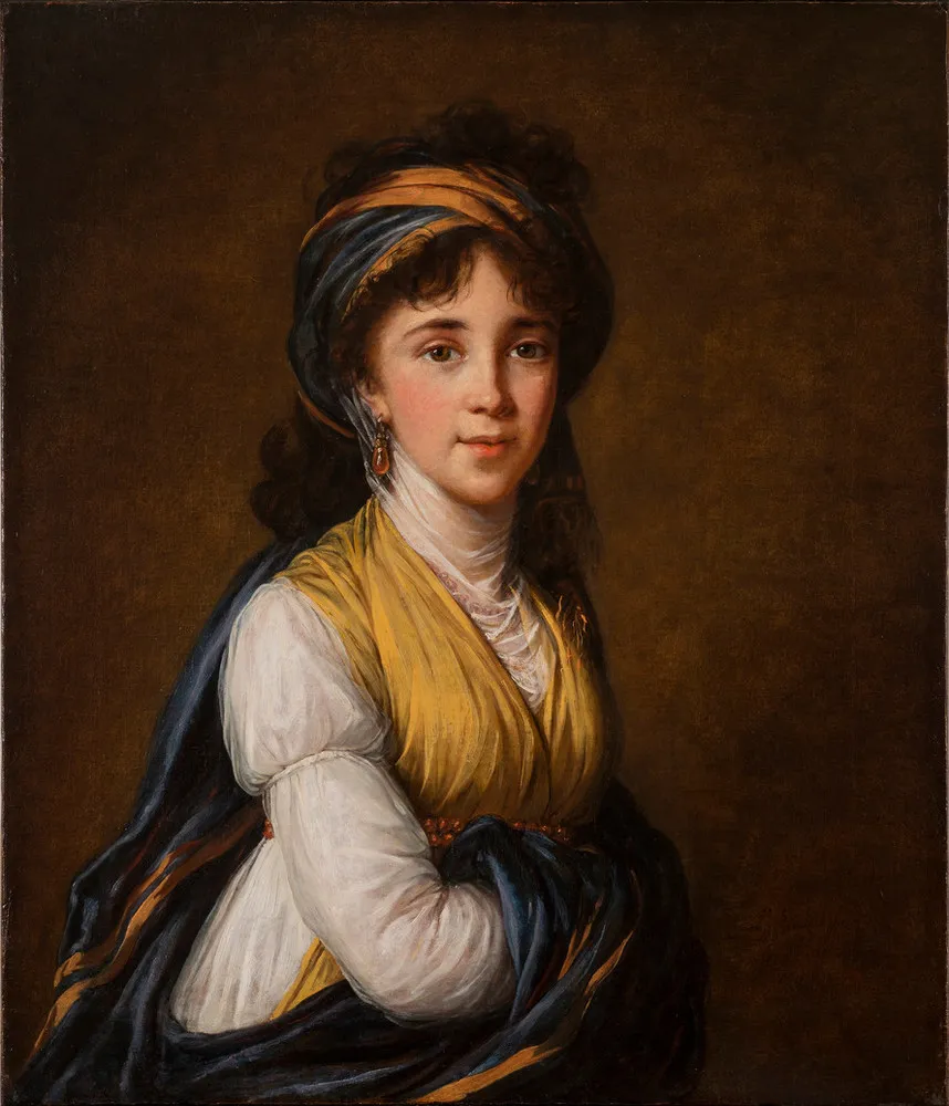 Realistically rendered half-portrait of a light-skinned young woman, gazing directly at the viewer with a faint smile on her lips. Her dark, curly hair is attractively tousled, secured under a turban-like headdress which matches her gold and blue draped ensemble.