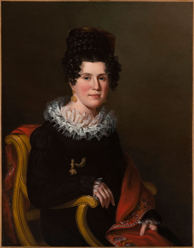 Side-by-side portraits of a husband and wife with light skin tone and dark hair sitting in formal postures. Gazing outward, they wear dark clothing with light accents and the woman wears a gold earring and pin. They both hold objects: the woman a brocaded red cloth and the man a book.