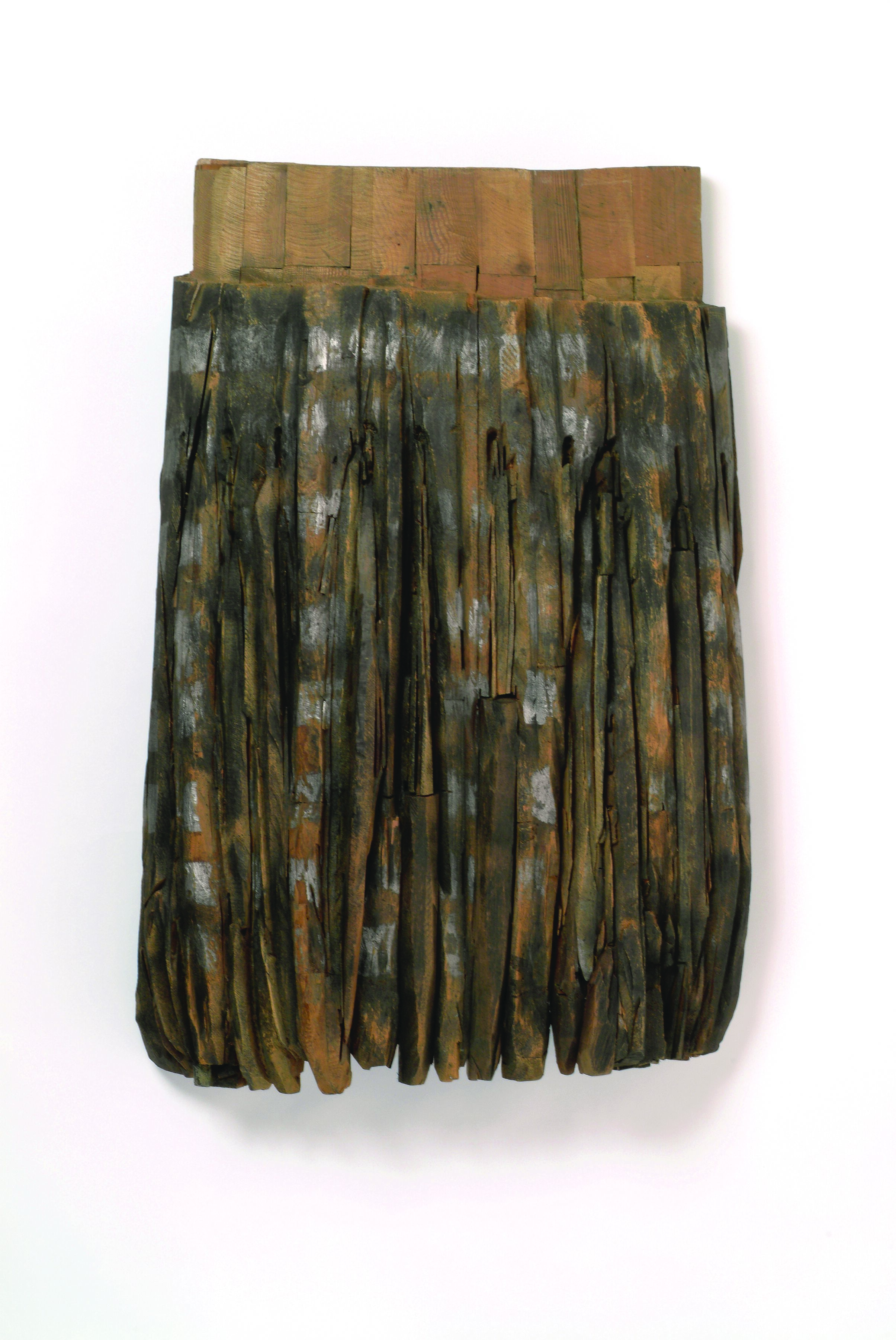Resembling the pleats and band of an apron, this large, one-sided, cedar sculpture features carved vertical lines darkened with graphite and stain beneath a solid band of natural-colored wood.