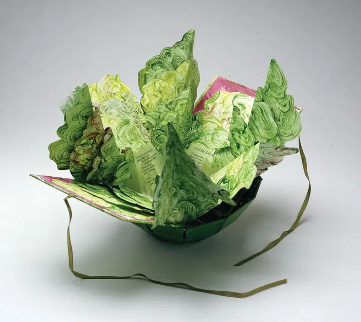 Artist's book resembling a salad in a bowl. Constructed of Tyvek that has been painted in swirling greens and map-folded to look like leaves of lettuce, there is poem written on the inner the leaves.