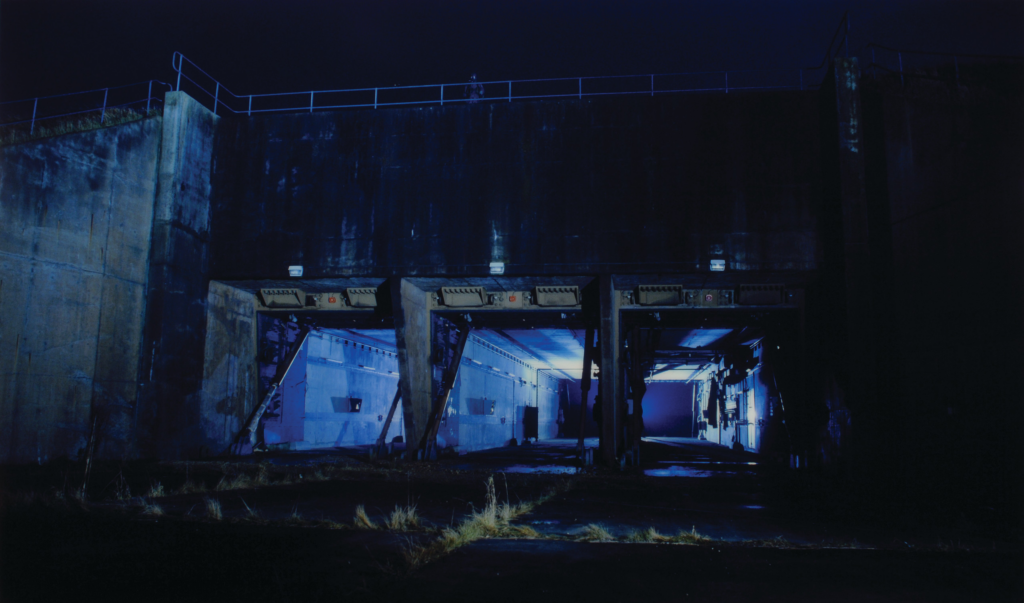 Eery photograph in blue tones of a concrete silo at night.
