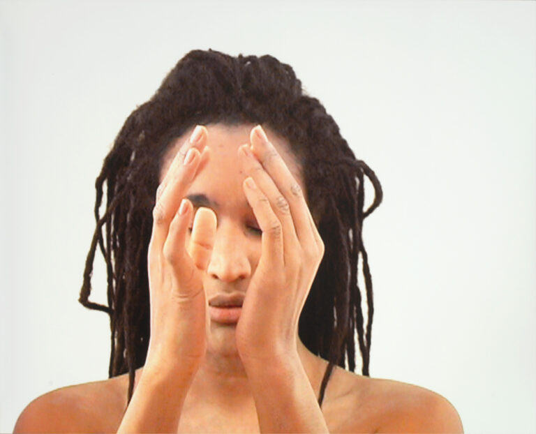 A woman with a medium skin tone holds her hands parallel in front of her face. Her eyes are closed and her head is slightly downturned. She is visible from the collarbones up.