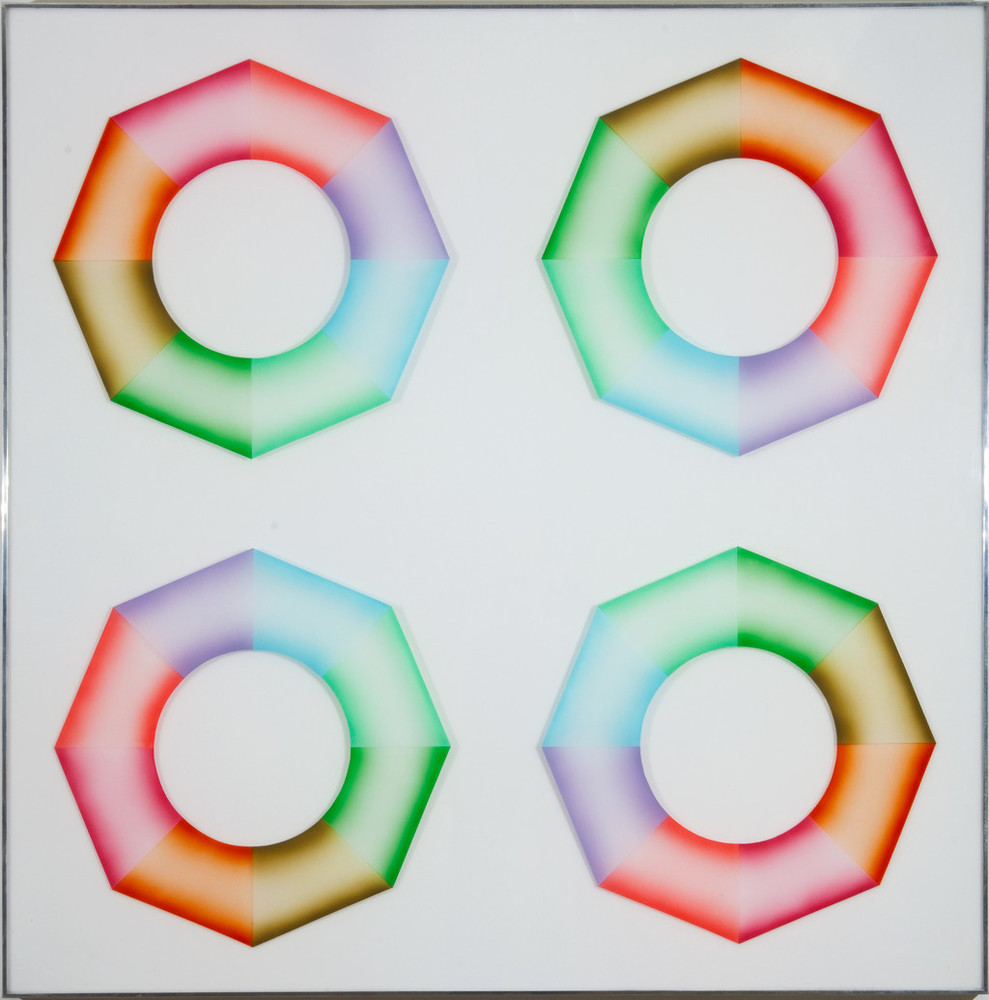 Four hard-edged octagonal rings, divided into wedges of brown, orange, pink, red, purple, blue, mint green, and grass green, sit on a square, white surface. Dark at the inner and outer edges and light in the center, the colors create the illusion of curved 3-dimensional objects.
