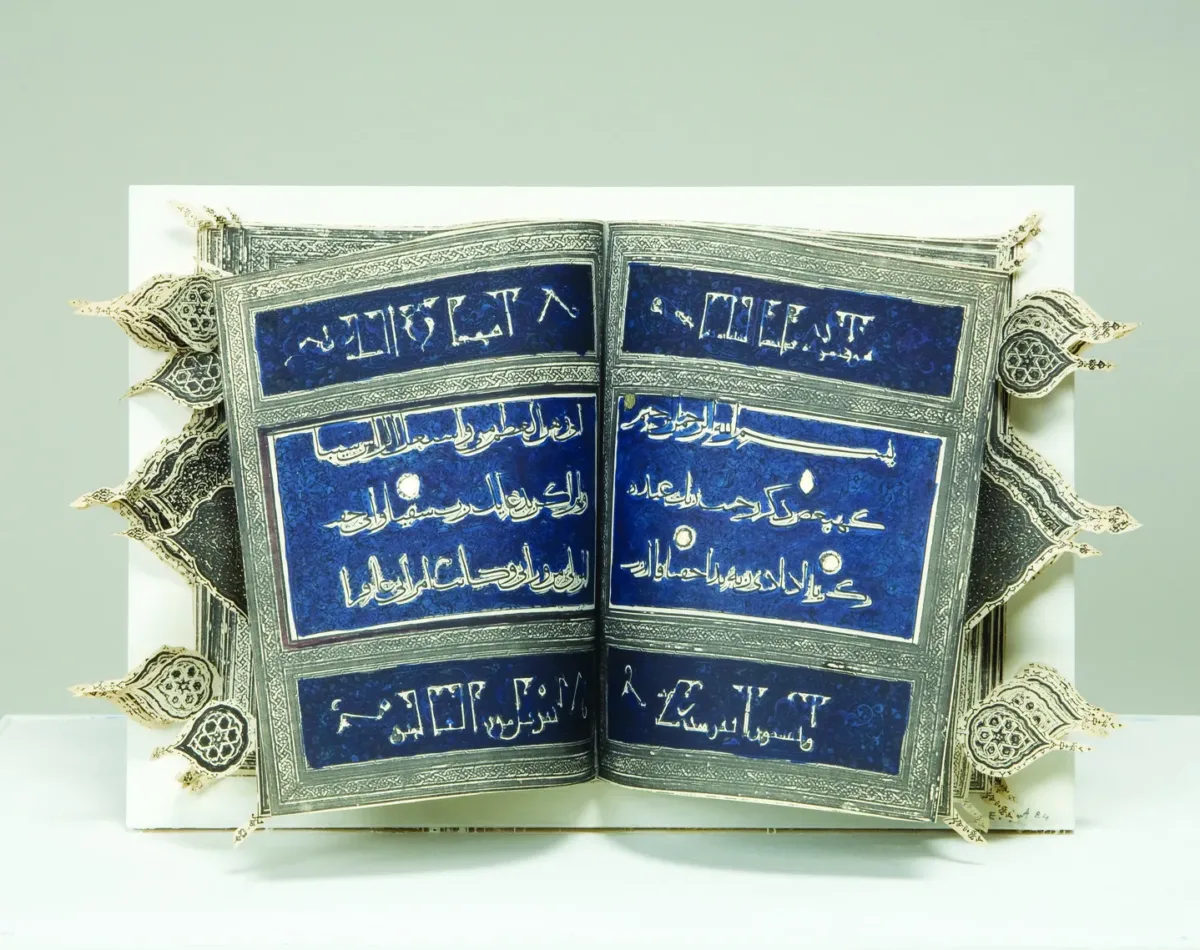 An open book with Arabic text on a dark blue background divided into horizontal sections by decorative silver border. Cut-out arabesques extend out beyond the edge of the book to the right and left.