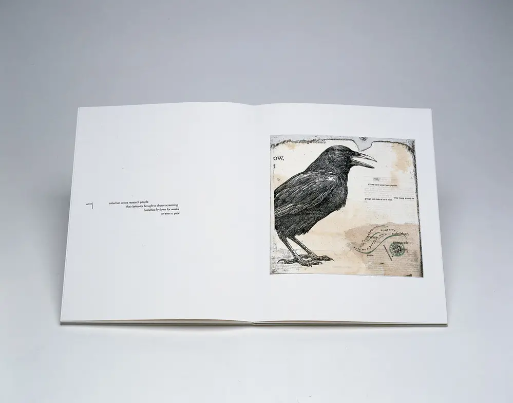 An open book is photographed on a white background. The pages shown are printed minimally. On the left are four small lines of text, right aligned in the center of the page. On the right is a square, rustic-looking collage with a black crow, the Starbucks logo, and some text.