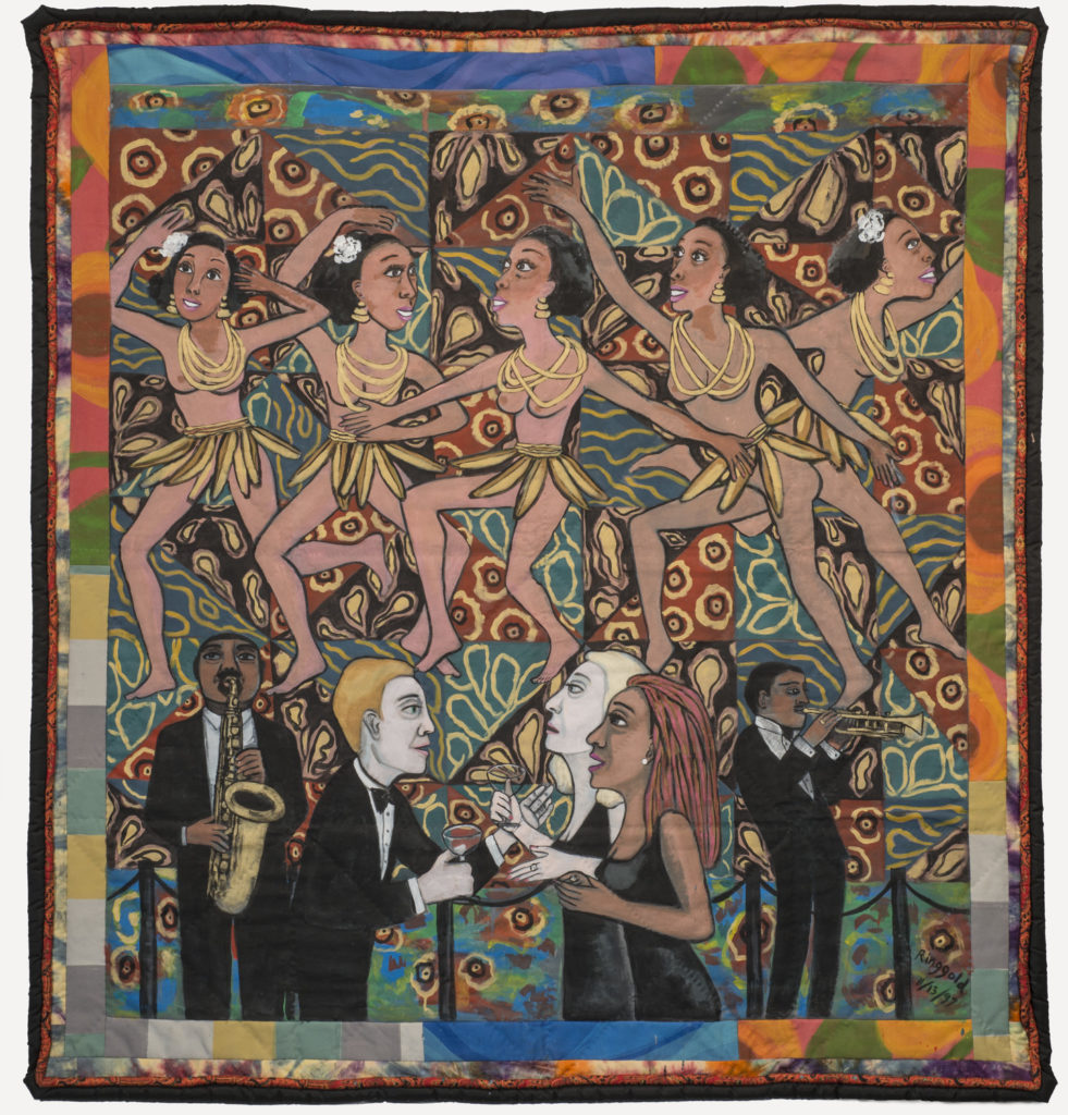 Colorful quilt with a multi-patterned background that depicts five medium skin toned, bare breasted dancing women wearing skirts of bananas and yellow necklaces. Below, from left to right, a medium-dark skin toned and light skin toned men and women interact and play brass instruments.