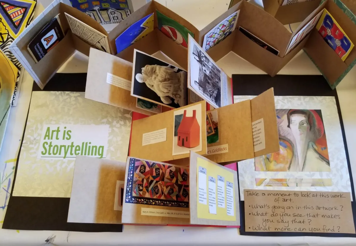 A birds-eyed view of a display of artists books showing a variety of folded paper and works of art.