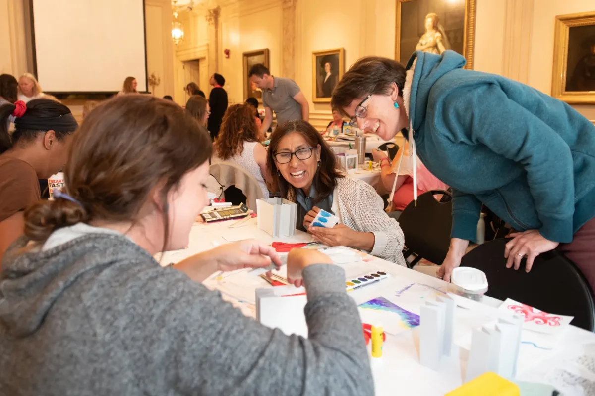 Three teachers at a table engaging in conversation and making tunnel books.