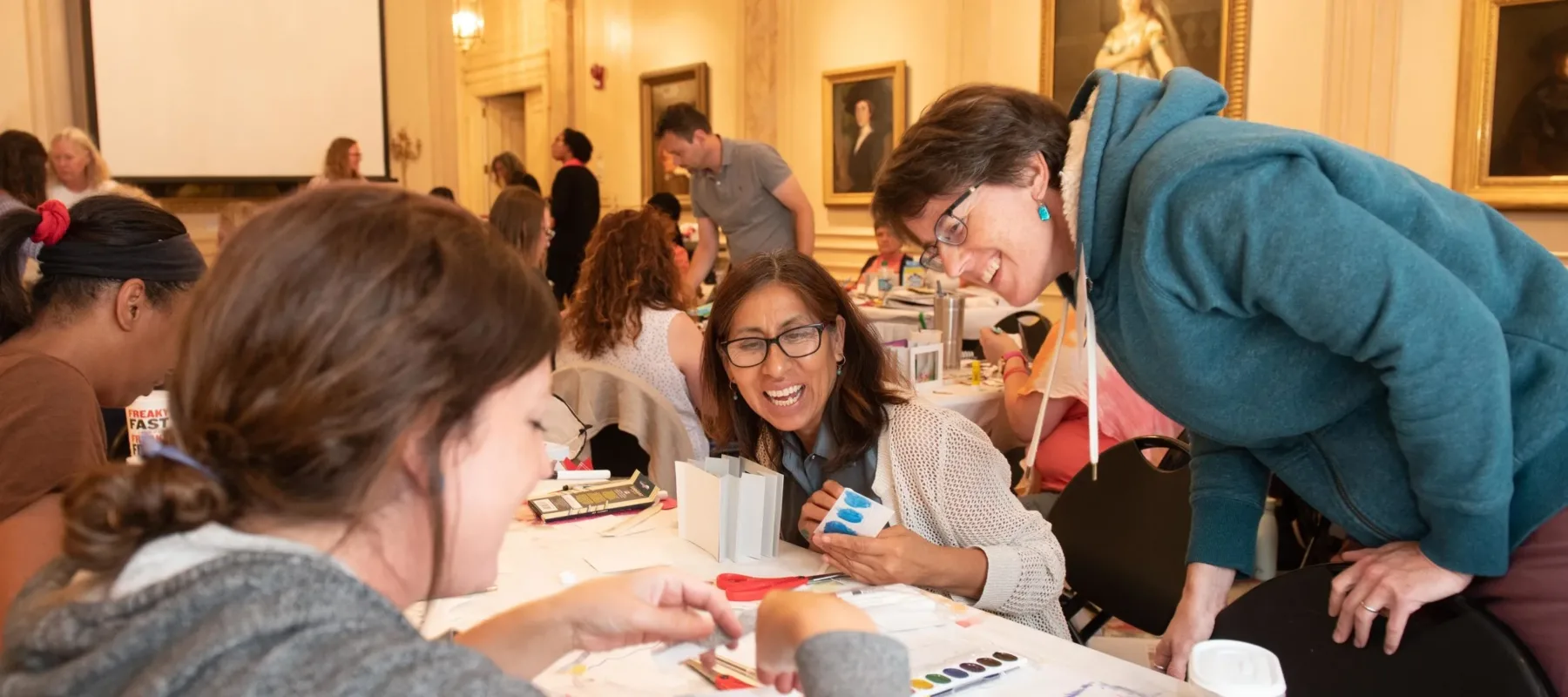 Three teachers at a table engaging in conversation and making tunnel books.