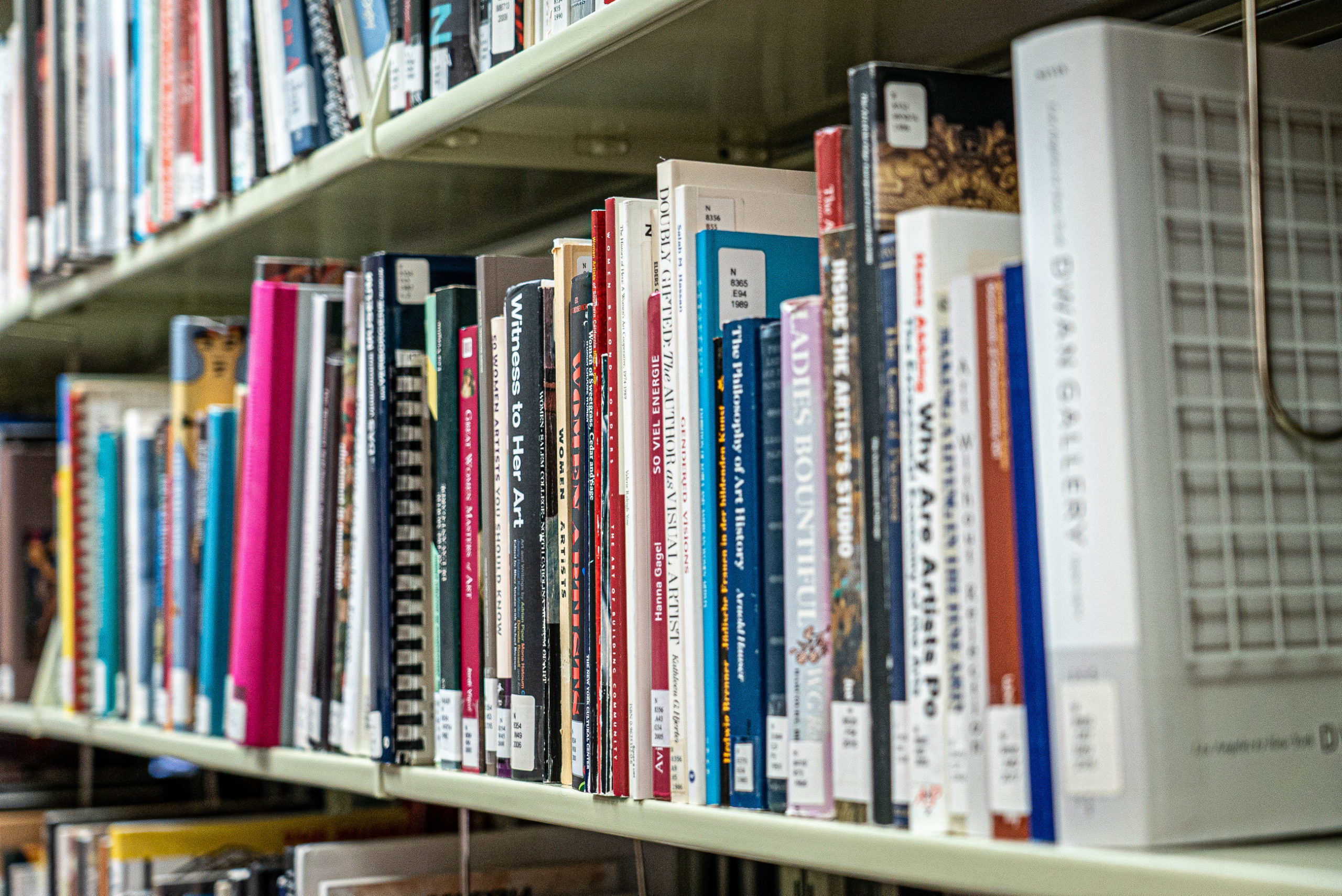 A bookshelf packed with colorful books about women artists.