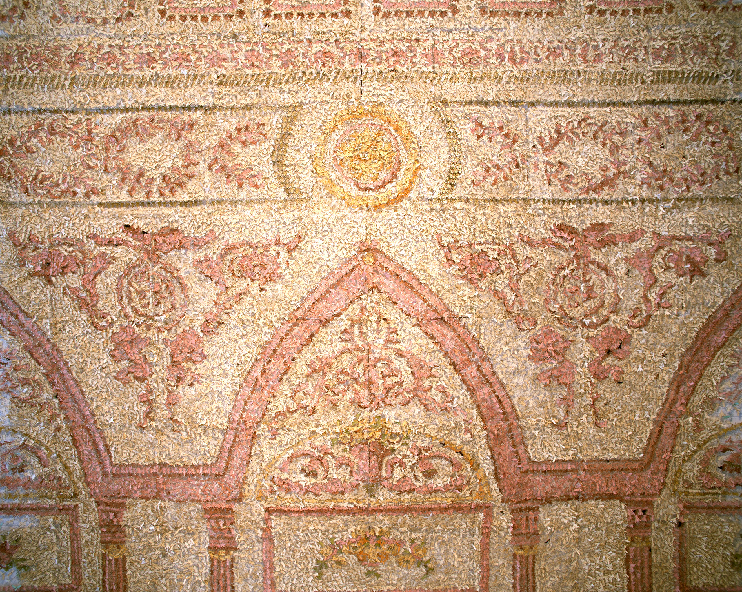 A colored image of what appears to be a wall decorated with mosaics in red and yellow tones. Upon closer inspection each shape is actually an origami bug.
