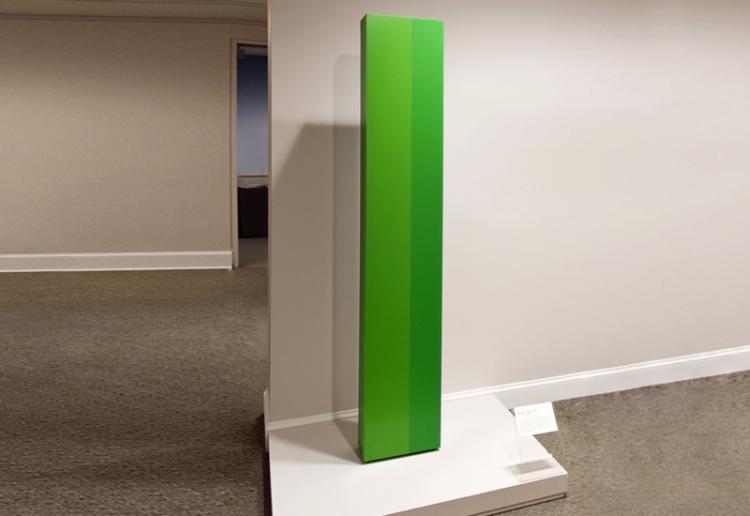 Tall, rectangular, pillar-like sculpture, painted in vibrant green hues on a smooth, clean surface.