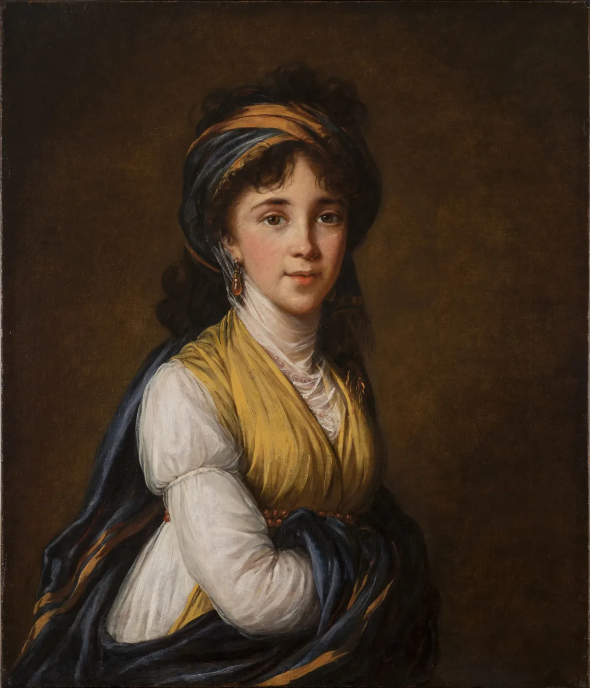 Realistically rendered half-portrait of a light-skinned young woman, gazing directly at the viewer with a faint smile on her lips. Her dark, curly hair is attractively tousled, secured under a turban-like headdress which matches her gold and blue draped ensemble.