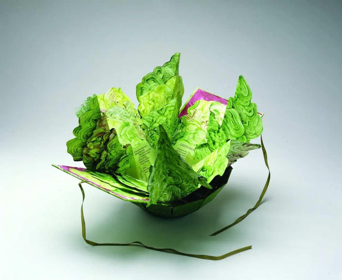 Artist's book resembling a salad in a bowl. Constructed of Tyvek that has been painted in swirling greens and map-folded to look like leaves of lettuce, there is poem written on the inner the leaves.