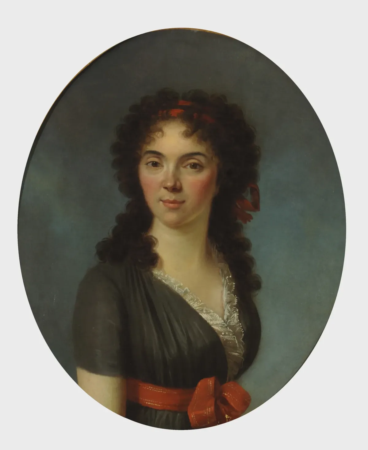 Oval portrait of a young woman with light skin gazes out at the viewer with her dark tousled curls framing her face and shoulders.