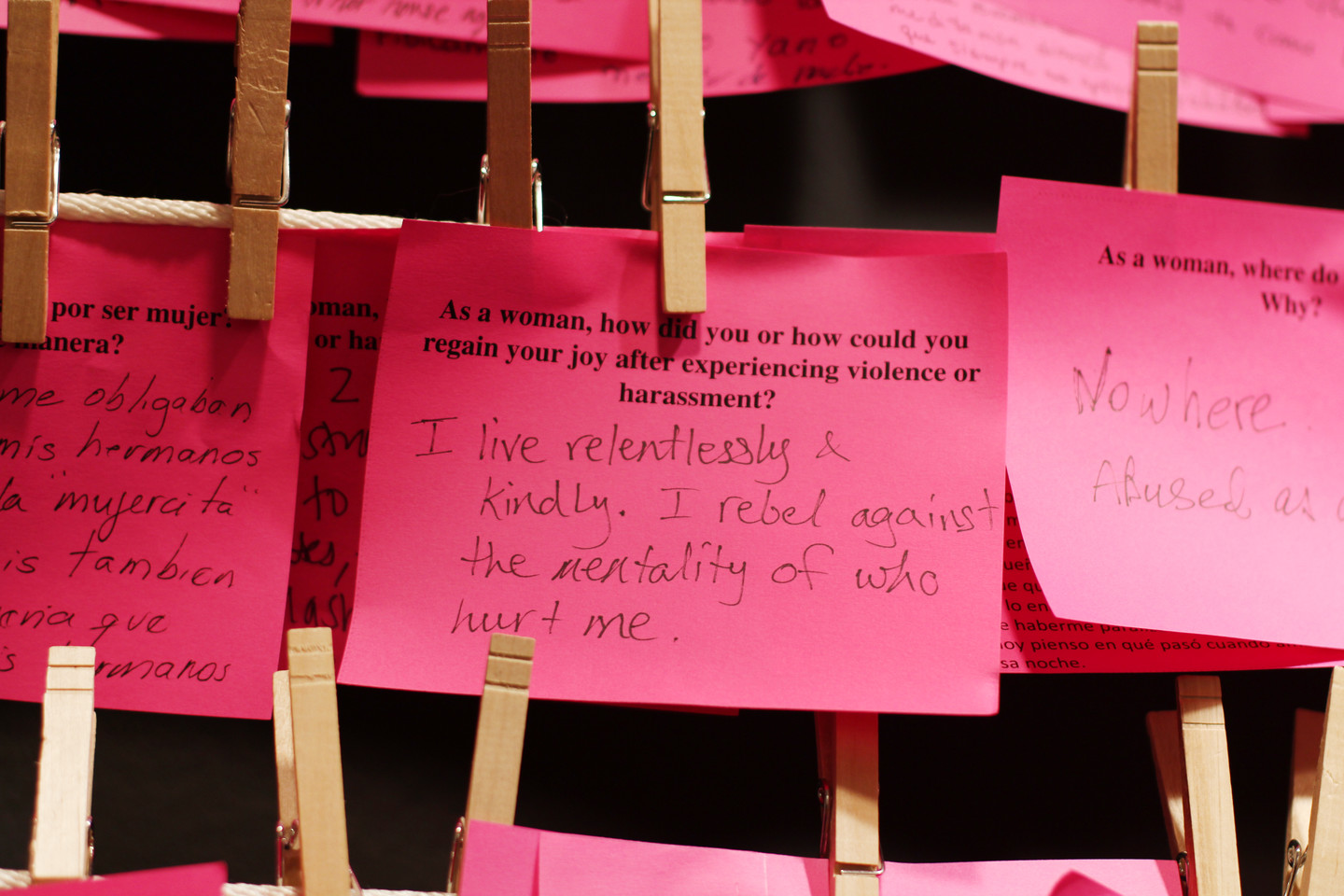 Multiple pink post-it notes hung on a clothesline with clothespins. There is a handwritten note in response to a typed question about regaining joy. The response is "I live relentlessly & kindly. I rebel against the mentality of who hurt me."