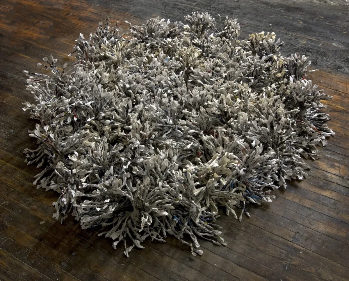 Six-square-diameter floor sculpture of shredded and twisted newspapers.